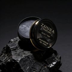 Zoura Guilt Trip Solid Perfume open jar on black rock
