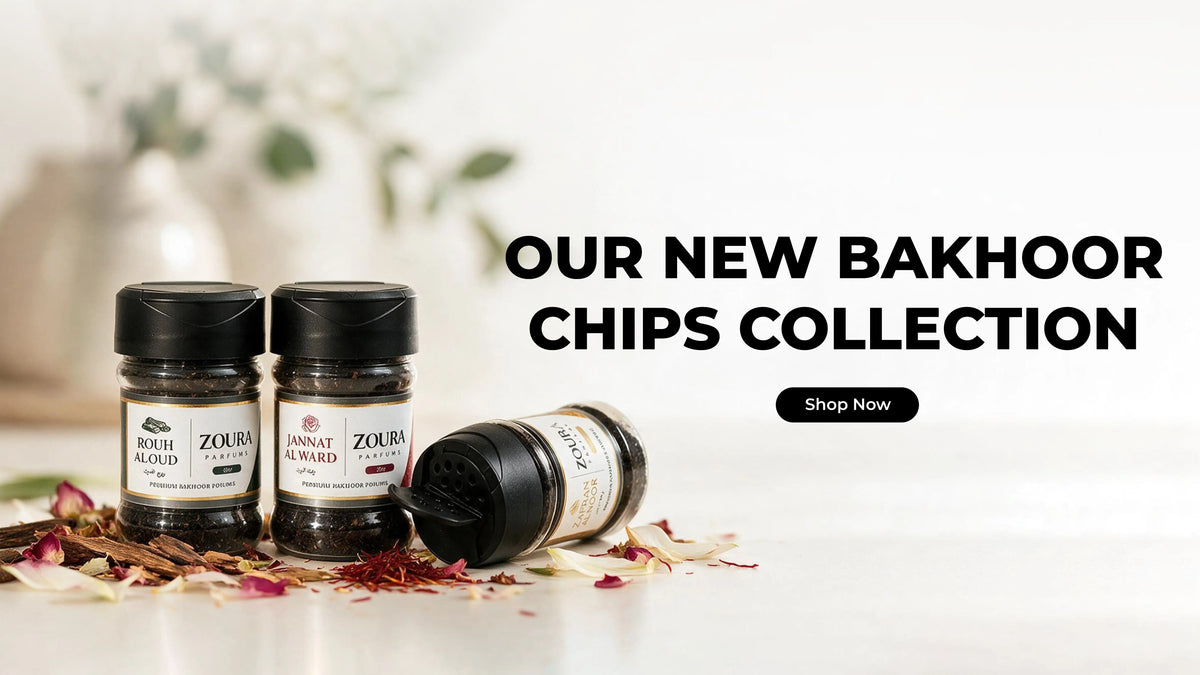 Three jars of Zoura Bakhoor Chips are displayed on a white surface with dried rose petals. One jar is upright on the left, another is upright on the right, and a third lies on its side in the center.