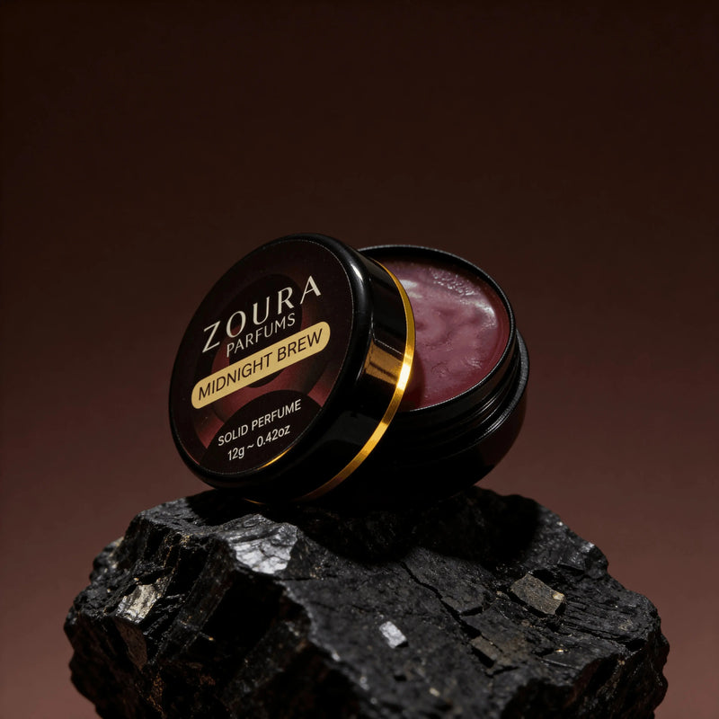 Open jar of Zoura Midnight Brew Unisex Solid Perfume resting on black charcoal stone