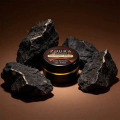 Zoura Midnight Brew Unisex Solid Perfume jar surrounded by gold-veined black rocks