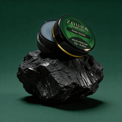 Open jar of Zoura Raw Edge Unisex Solid Perfume resting on black charcoal stone
